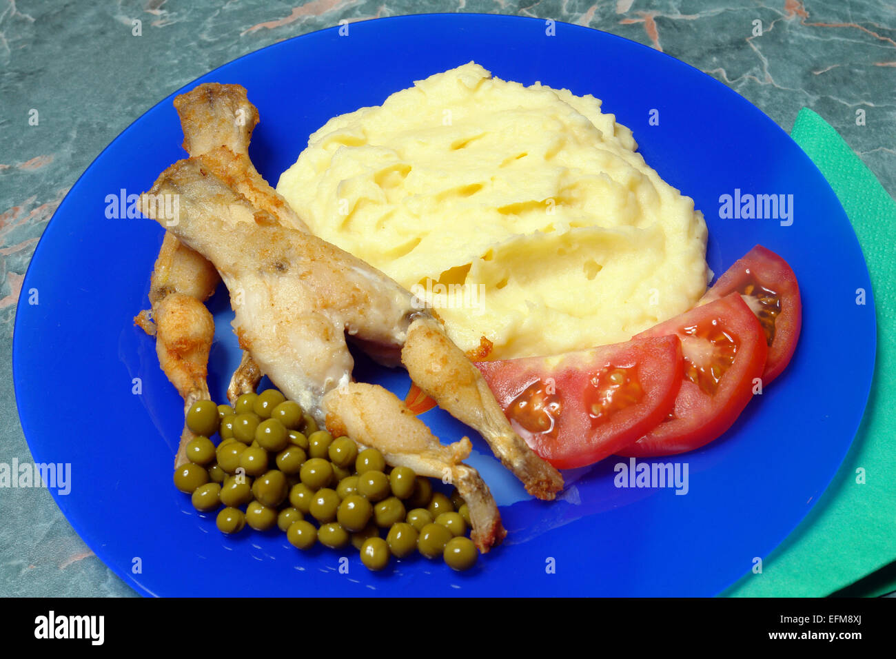 frog thigh with garnish on blue plate Stock Photo