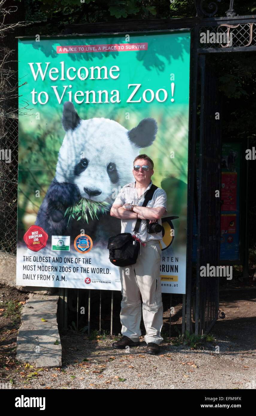 male tourist standing next to panda picture at entrance to vienna zoo Stock Photo