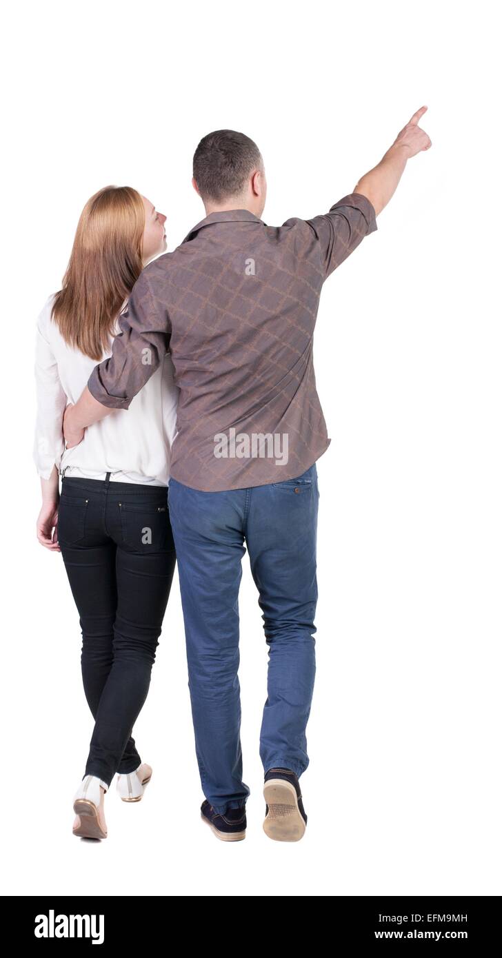 Back view of walking young couple (man and woman) pointing. Rear view ...