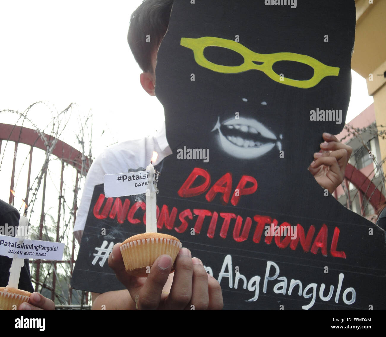 A Filipino protester holds a cupcake candle and a shadow cut-out of President Benigno Aquino III near Malacanang presidential palace, a day before the latter's 55th birthday. Each cut-out contains topics that hound the nation, one of which is the Disbursement Acceleration Program (DAP), a spending mechanism that was recently declared unconstitutional by the Supreme Court. The hashtag '#(Nasaan)AngPangulo' reads in English as, 'Where is the President?' © Richard James Mendoza/Pacific Press/Alamy Live News Stock Photo