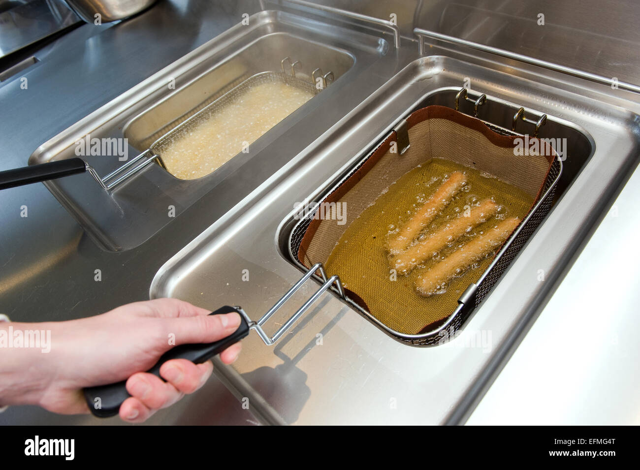 Three deepfried sausages and french fries baking in fat in a cafetaria