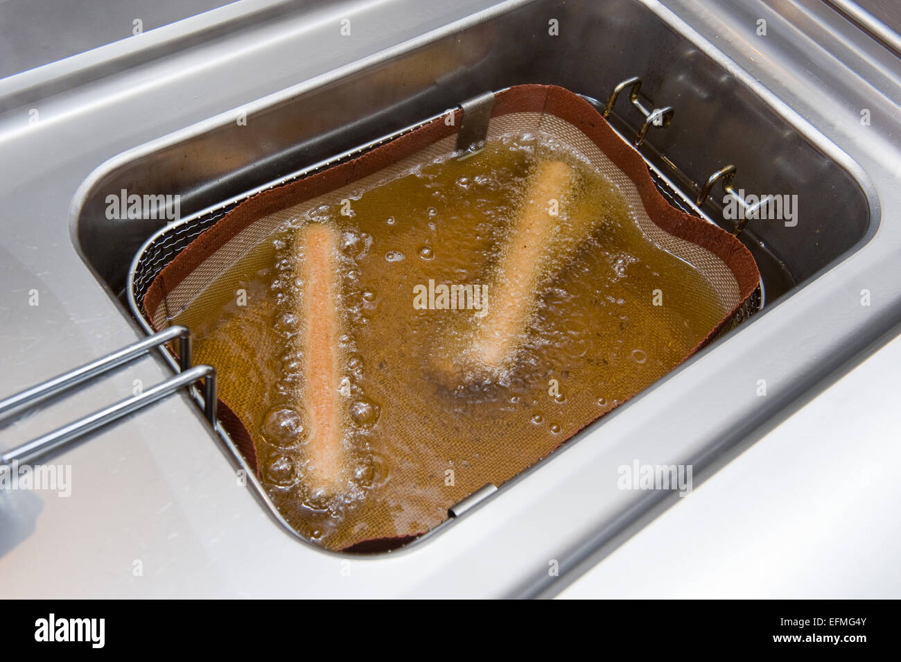 Two deep-fried sausages baking in fat in a pan basket Stock Photo