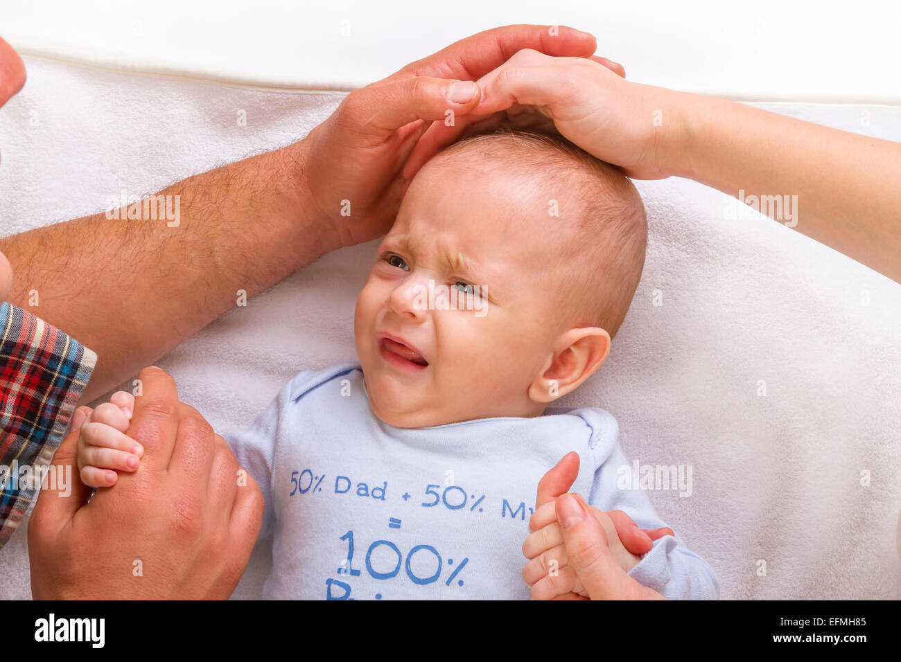 Parents calm a crying baby stroking it on his head Stock Photo