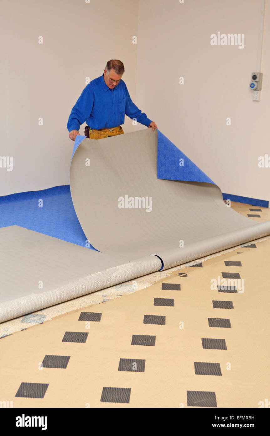 A floorlayer carefully pulls back the new carpet before applying