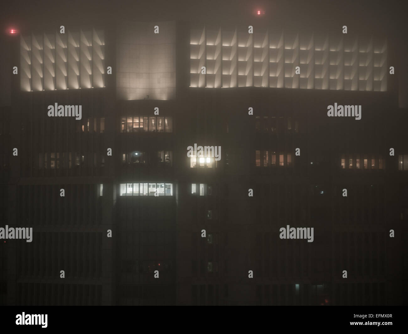 Tokyo skyscraper's lights glow in the fog at night Stock Photo
