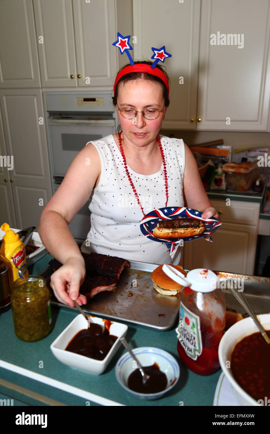 Caucasian female in her thirties serving herself at buffet lunch at home for 4th July Independence Day, USA Stock Photo