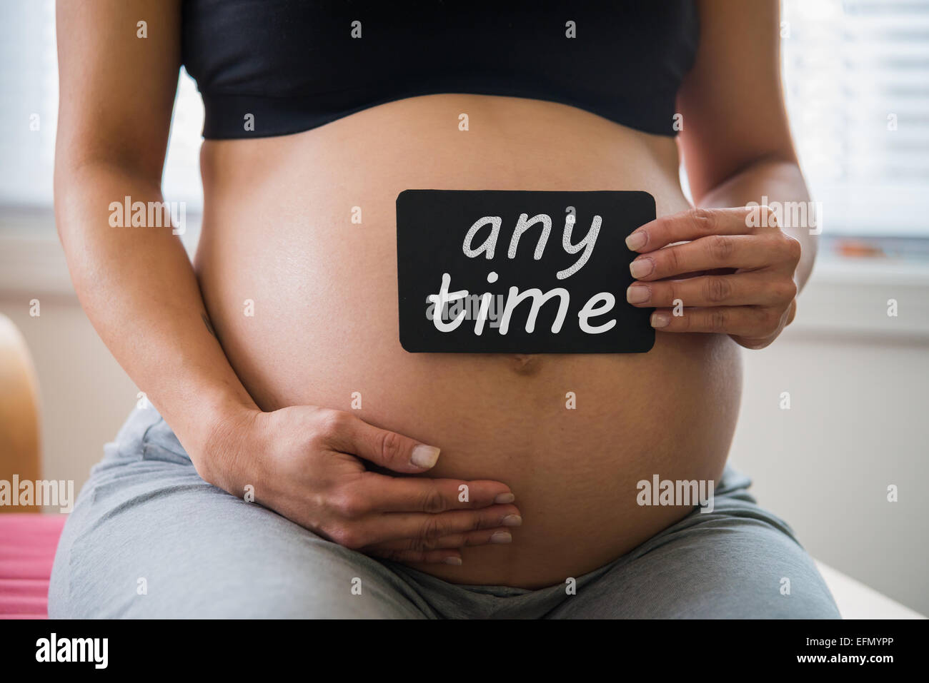 Baby bump, Image of 8 month pregnant woman holding a sign over her belly Stock Photo