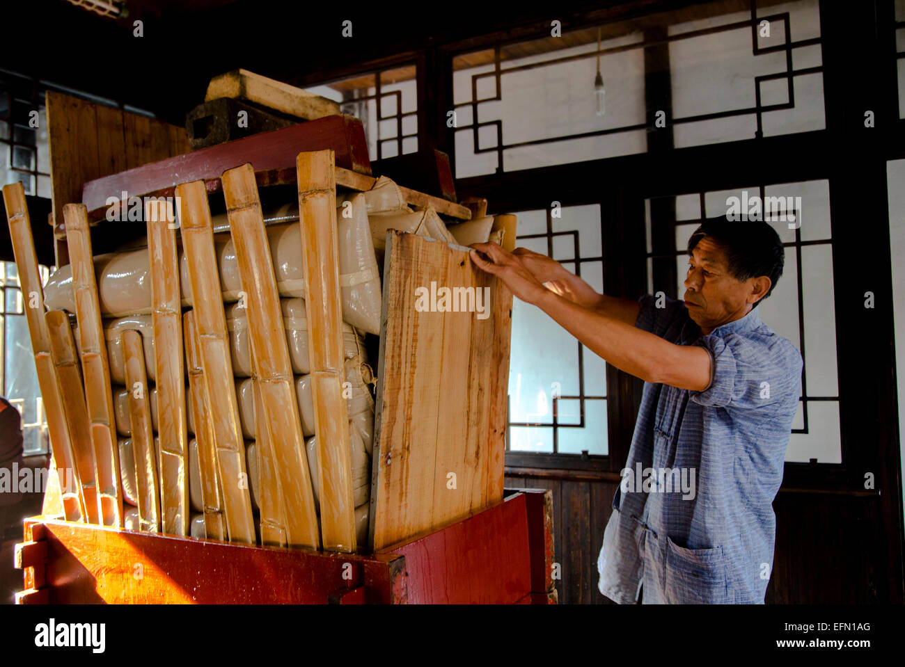 traditional brewing technique of Chinese rice wine a man is pressing the fermented mash to