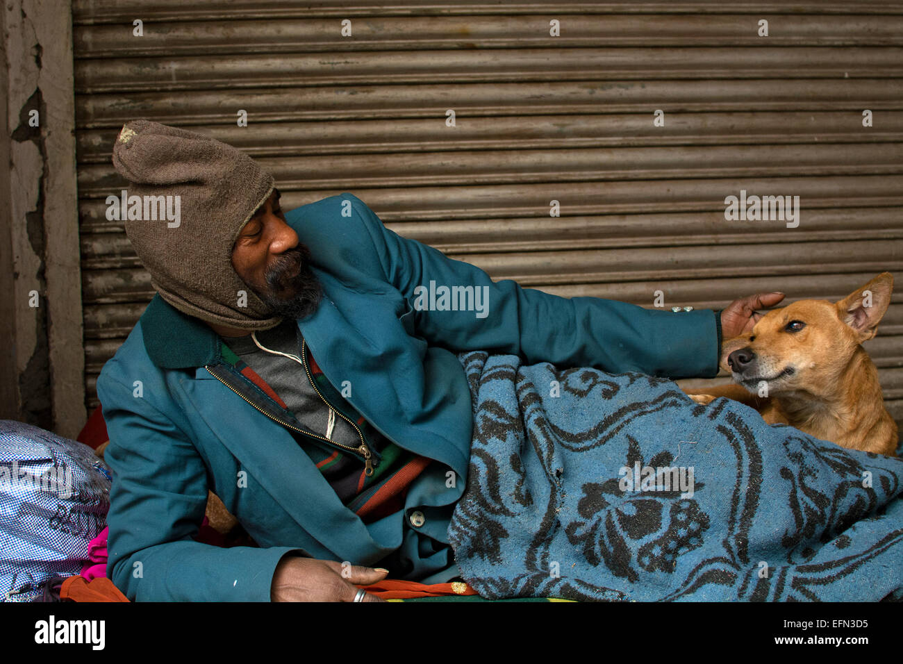 homeless man,stray dog,love,affection,street,India,co-existence,winter,poverty,pavement-dweller,friends,companions,care Stock Photo