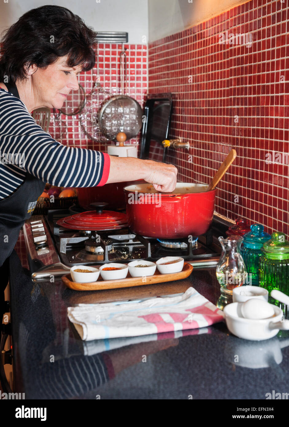 Woman stirring a red pot on the stove during a cooking class, Bellavista district, Santiago, Chile, South America Stock Photo