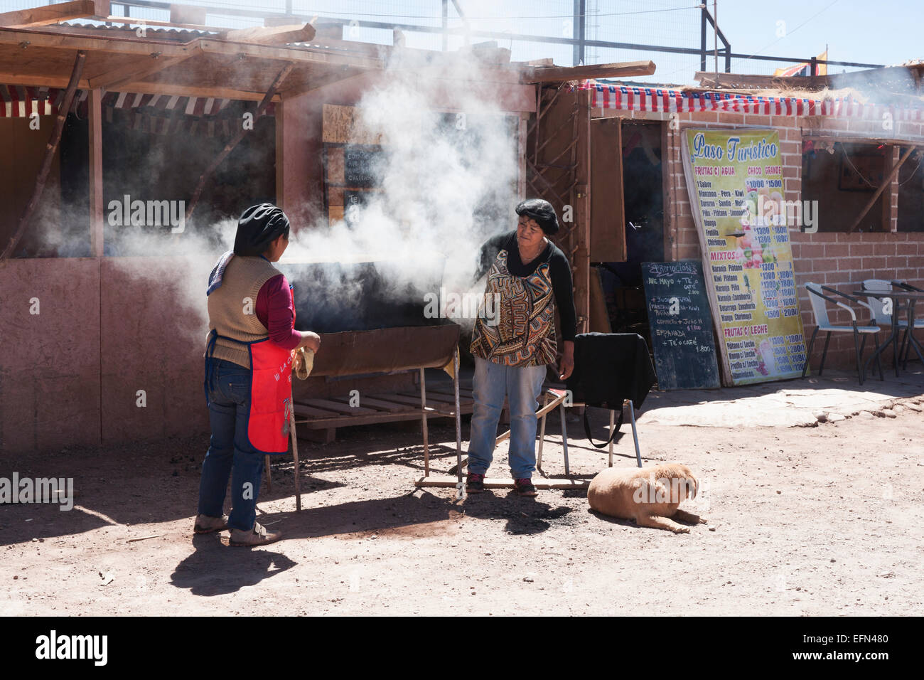 Two women barbequeing on a grill outside a restaurant preparing for the local celebration on Sept 18, Independence Day, with BBQ Stock Photo