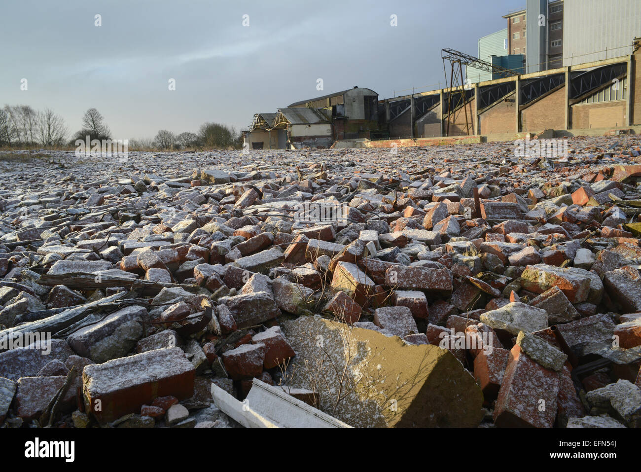 piles of rubble on derelict land and factory building covered by winter snow near selby yorkshire united kingdom Stock Photo