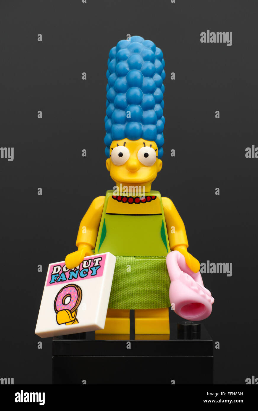 Lego Marge Simpson minifigure with pink purse and magazine Donut Fancy on black background Stock Photo