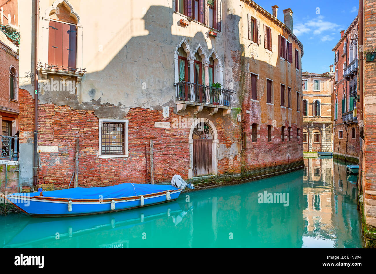 Boat on narrow canal among old brick houses in Venice, Italy. Stock Photo
