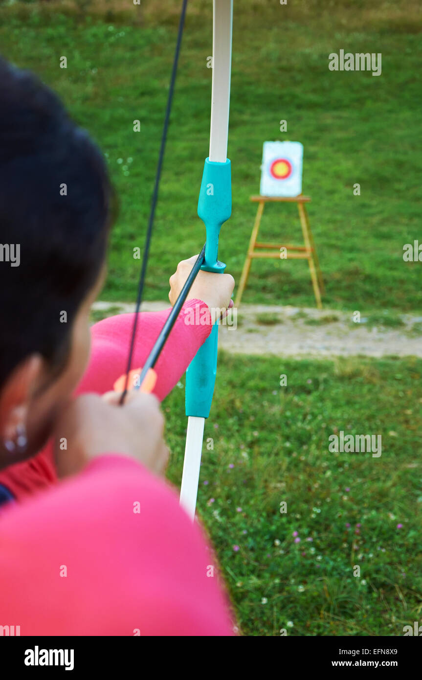 Target and woman-archerres is aiming with bow Stock Photo