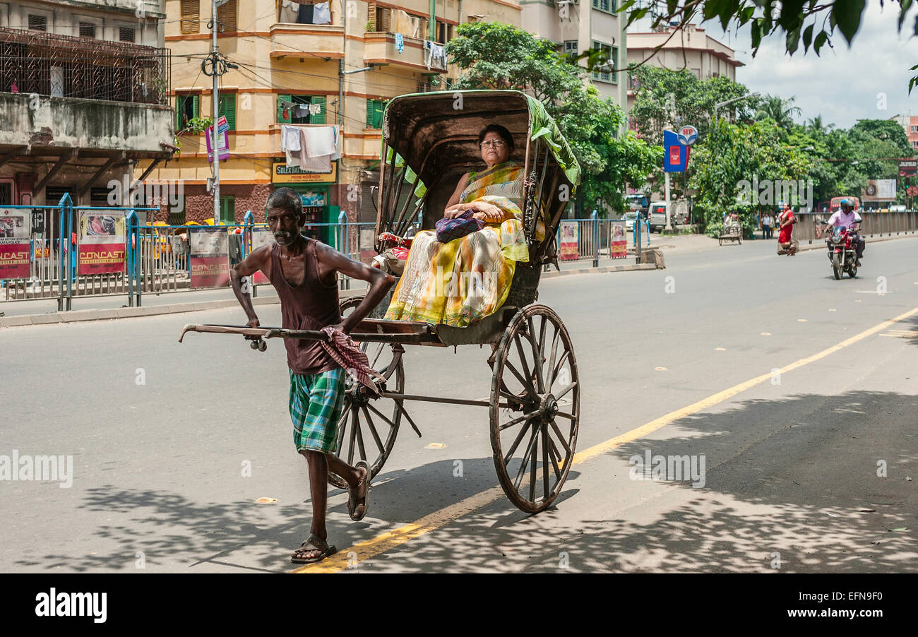 A man pulls a wooden rickshaw with passenger along a street on August 19, 2011 in Kolkata, India. Stock Photo