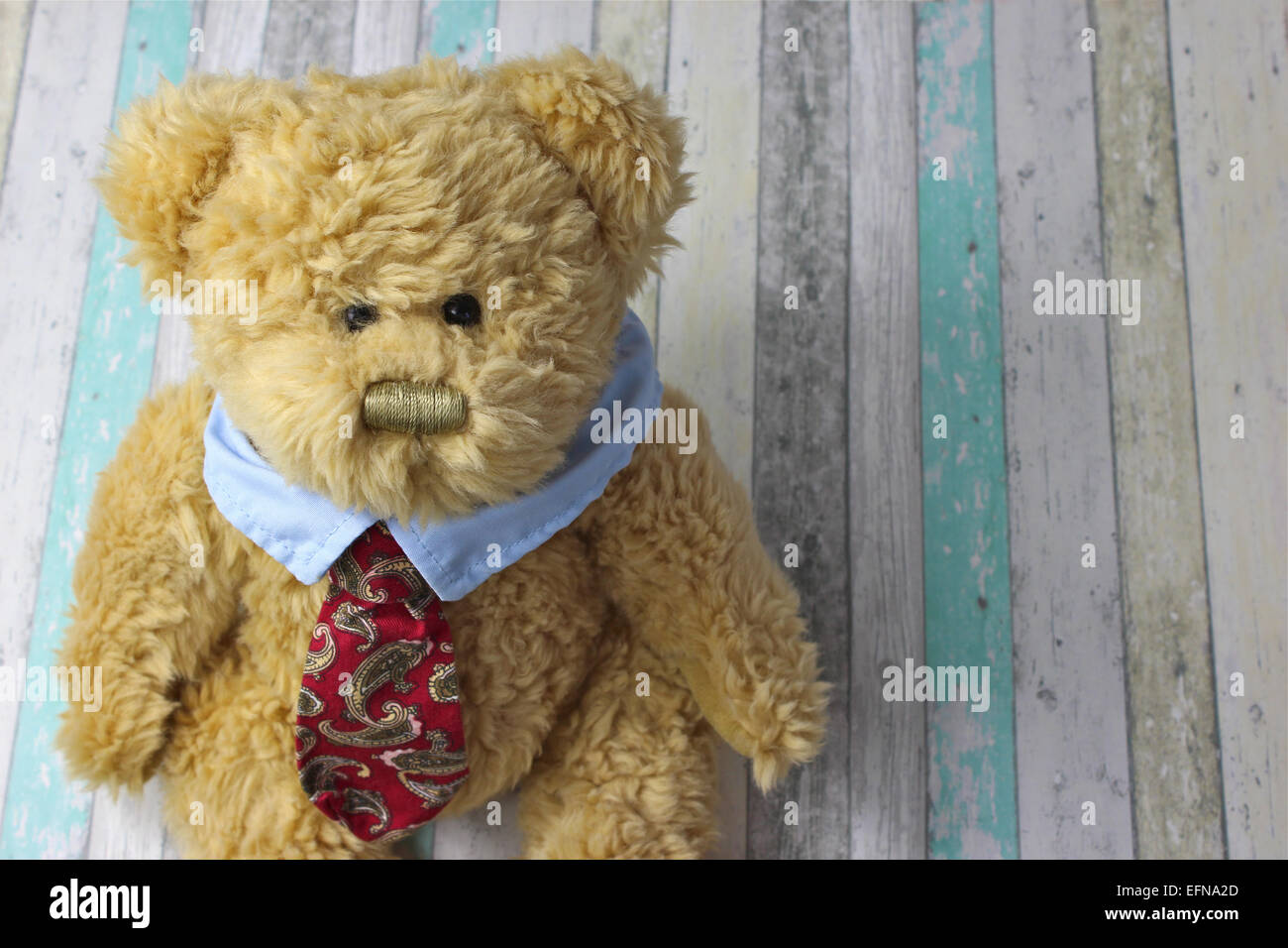 Office teddy bear dressed in shirt and tie against a rustic wooden background. Stock Photo