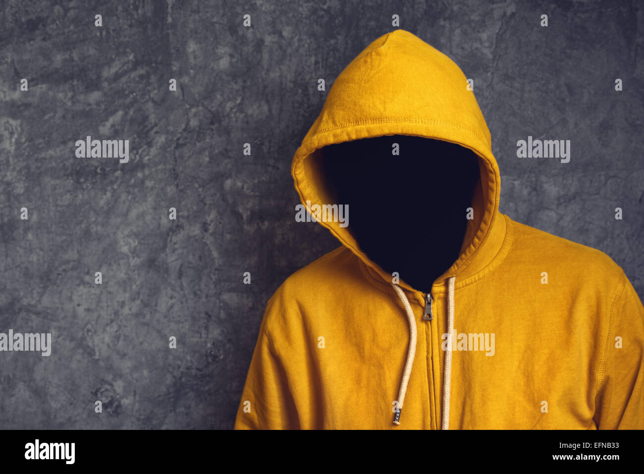 Faceless unknown and unrecognizable person without identity wearing yellow hooded jacket. Stock Photo