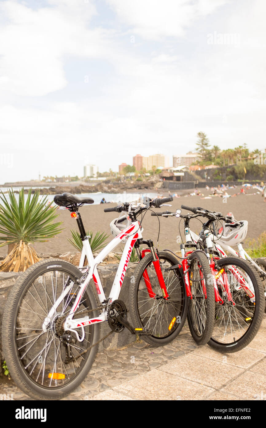 Mountain bikes parked on the promenade with a view of Playa Jardin beach in the background, Puerto de la Cruz, Tenerife Stock Photo
