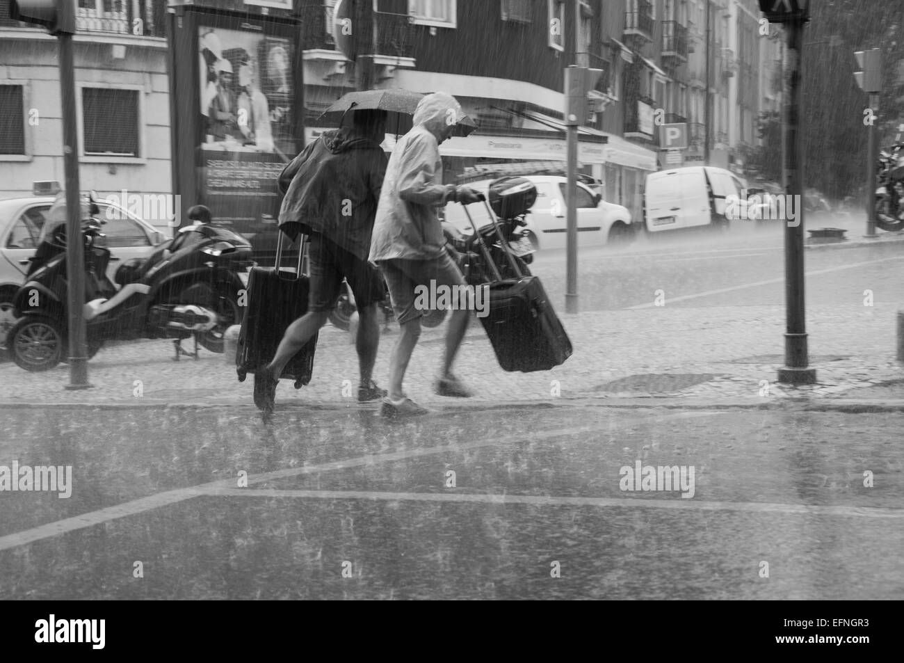 Black and white photo of two people running on the street under heavy rain Stock Photo