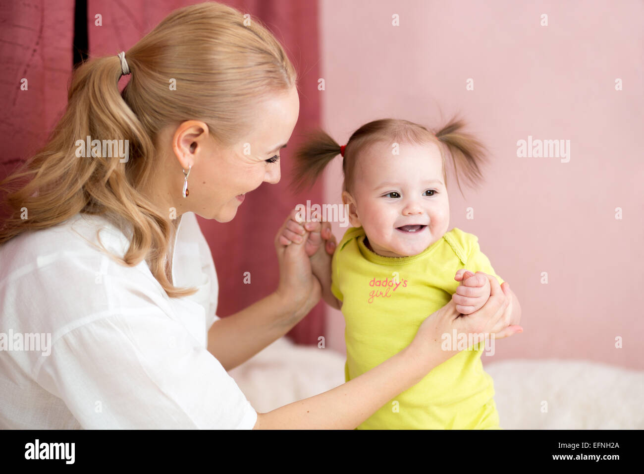 Happy mother holding baby hands Stock Photo