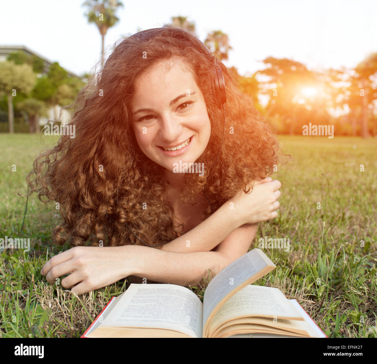 girl reading on meadow with headphone Stock Photo