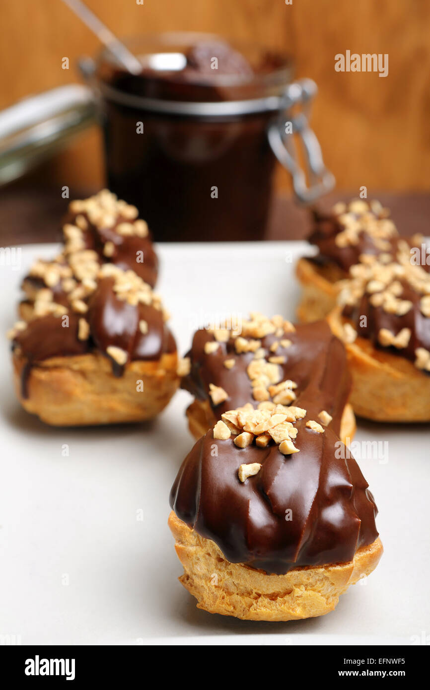 Eclairs with chocolate and nuts on plate on wooden background Stock Photo