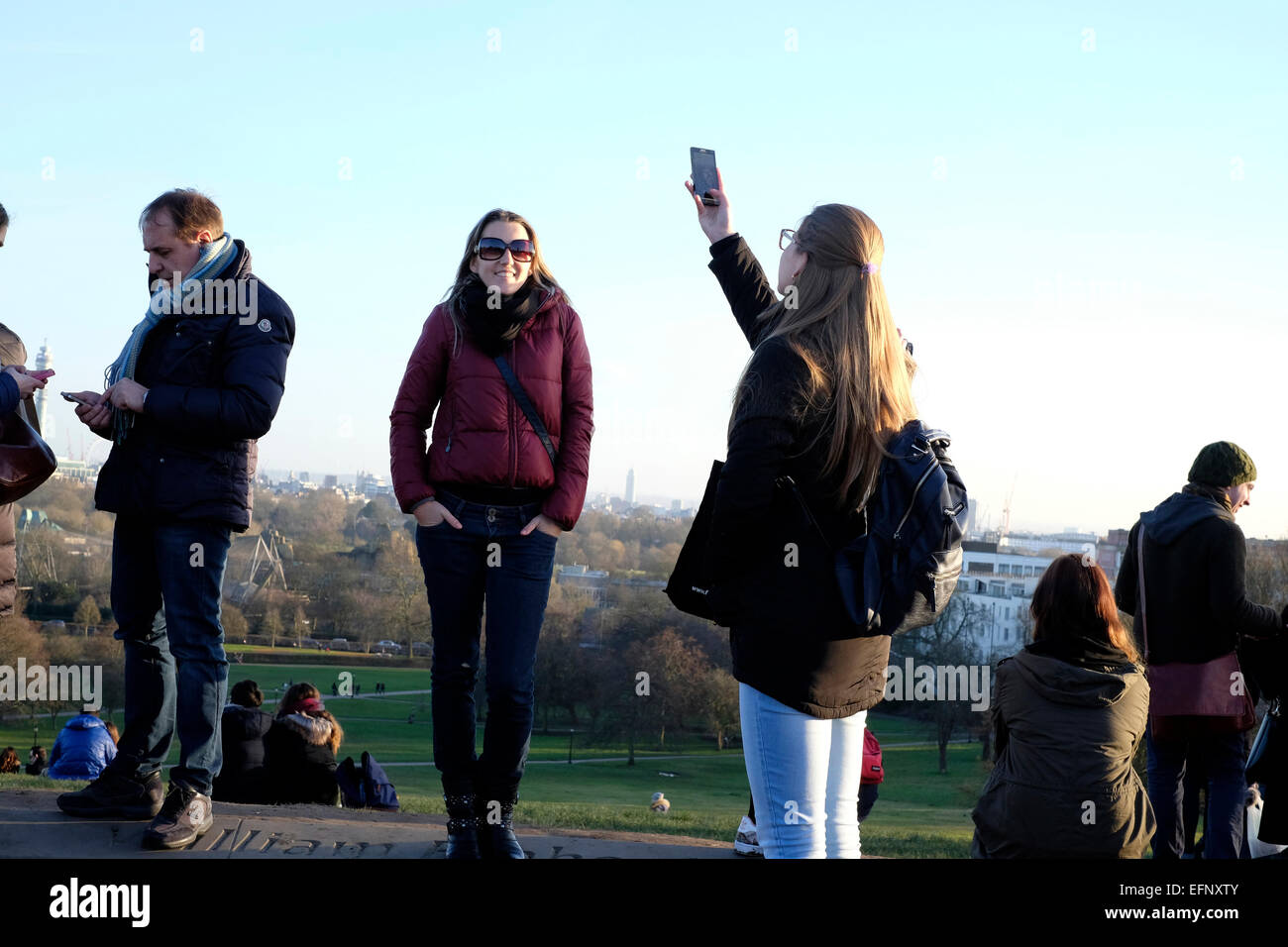 A woman taking photos with a smart phone in Primrose Hill, London Stock Photo