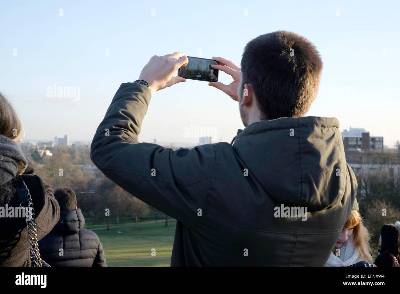 A man taking photos with a smart phone in Primrose Hill, London Stock Photo