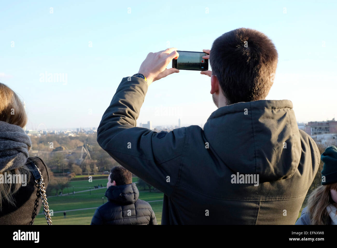 A man taking photos with a smart phone in Primrose Hill, London Stock Photo