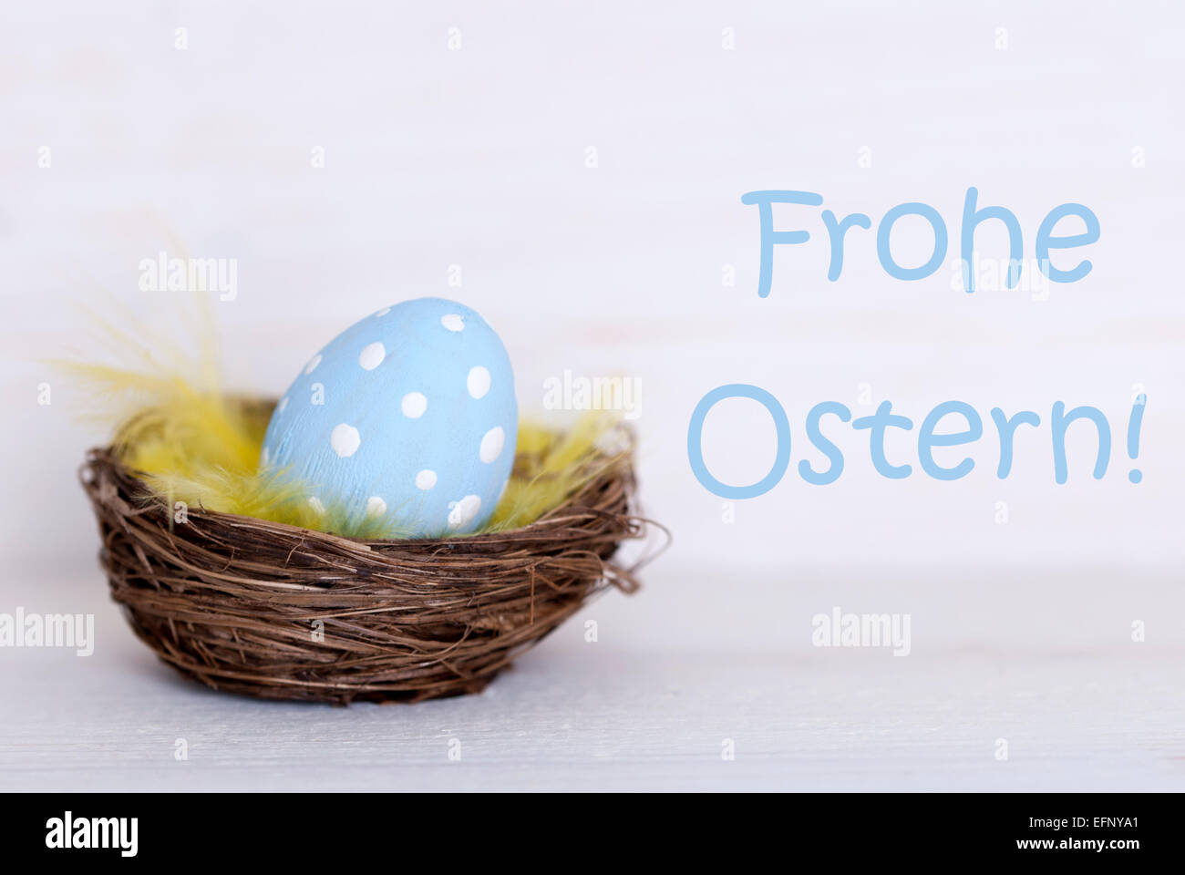 One Blue Dotted Easter Eggs In Easter Basket Or Nest On White Wooden Background With German Text Frohe Ostern Means Happy Easter Stock Photo