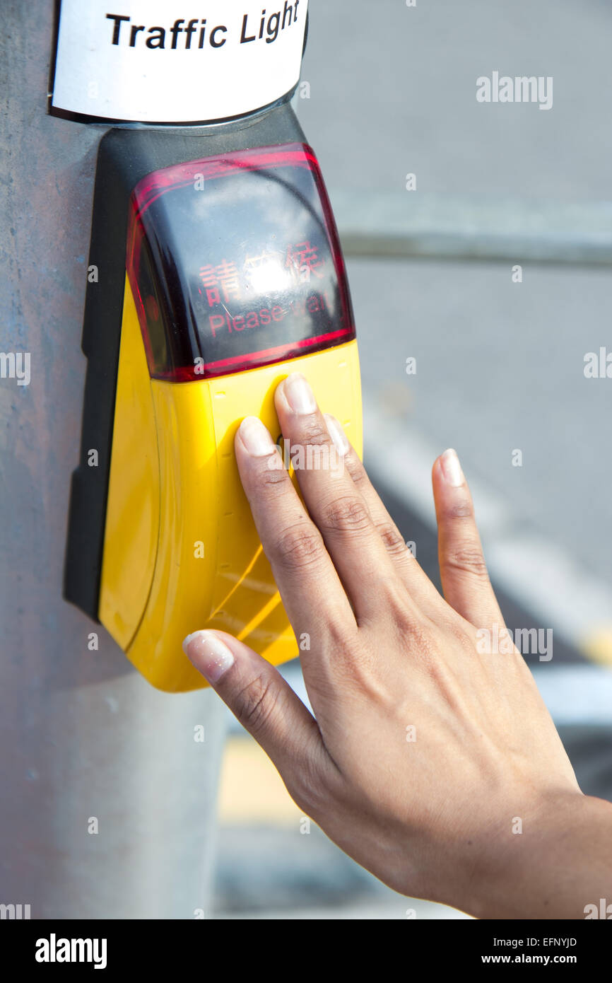 hand presses the button on the pedestrian crossing Stock Photo