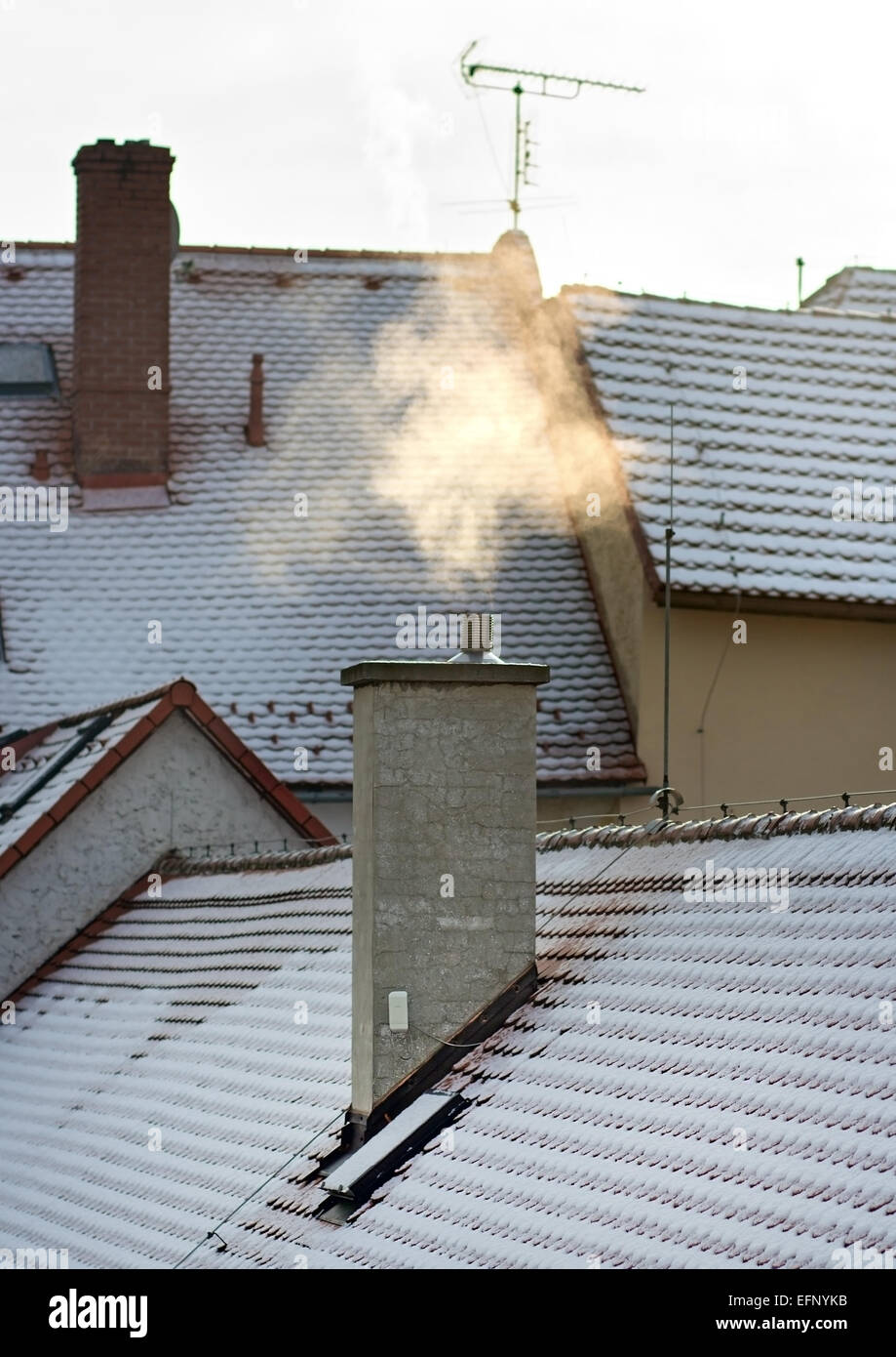 Smoke rising from the chimney in winter city Stock Photo