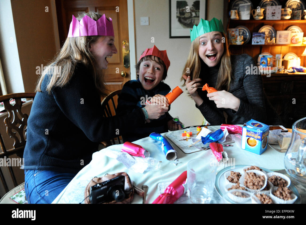 Three young cousins pulling crackers at the Christmas dinner table. Stock Photo
