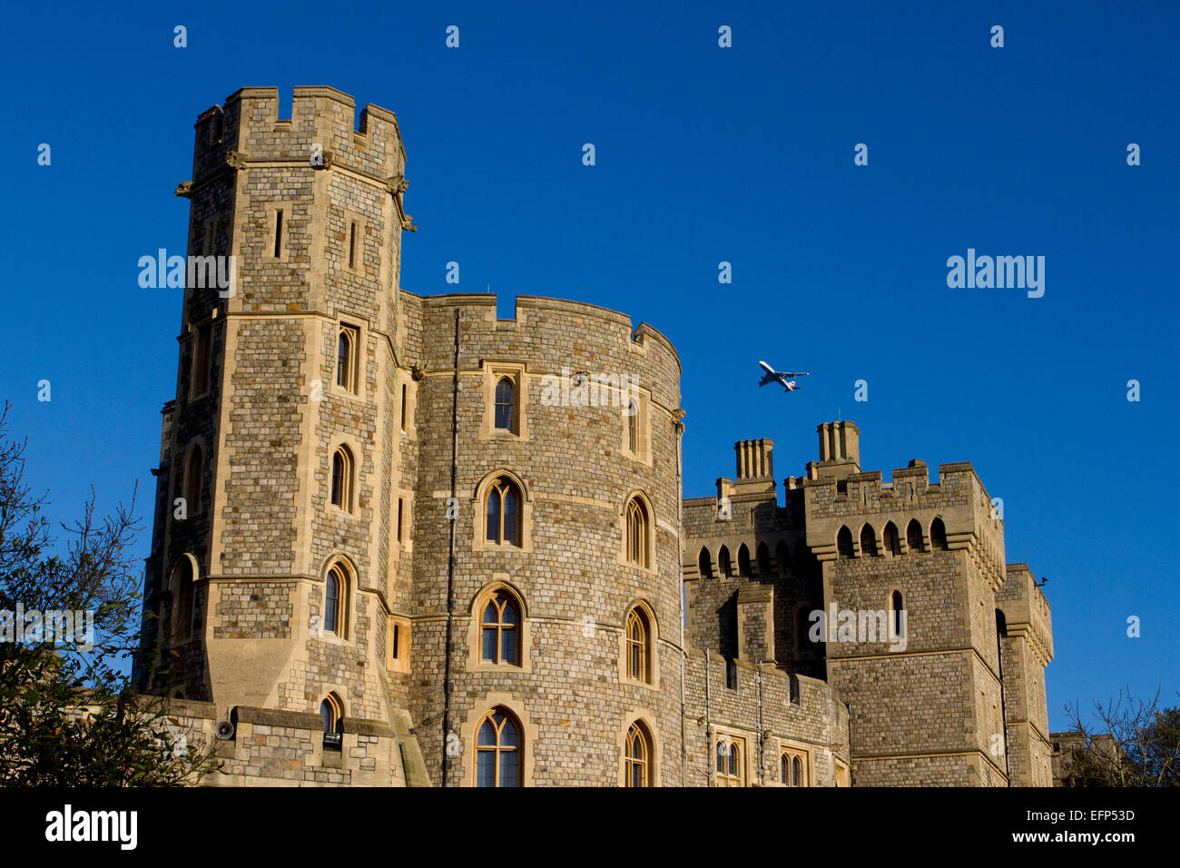 King Edward III Tower at Windsor Castle, Berkshire, England with airplane flying overhead in January Stock Photo