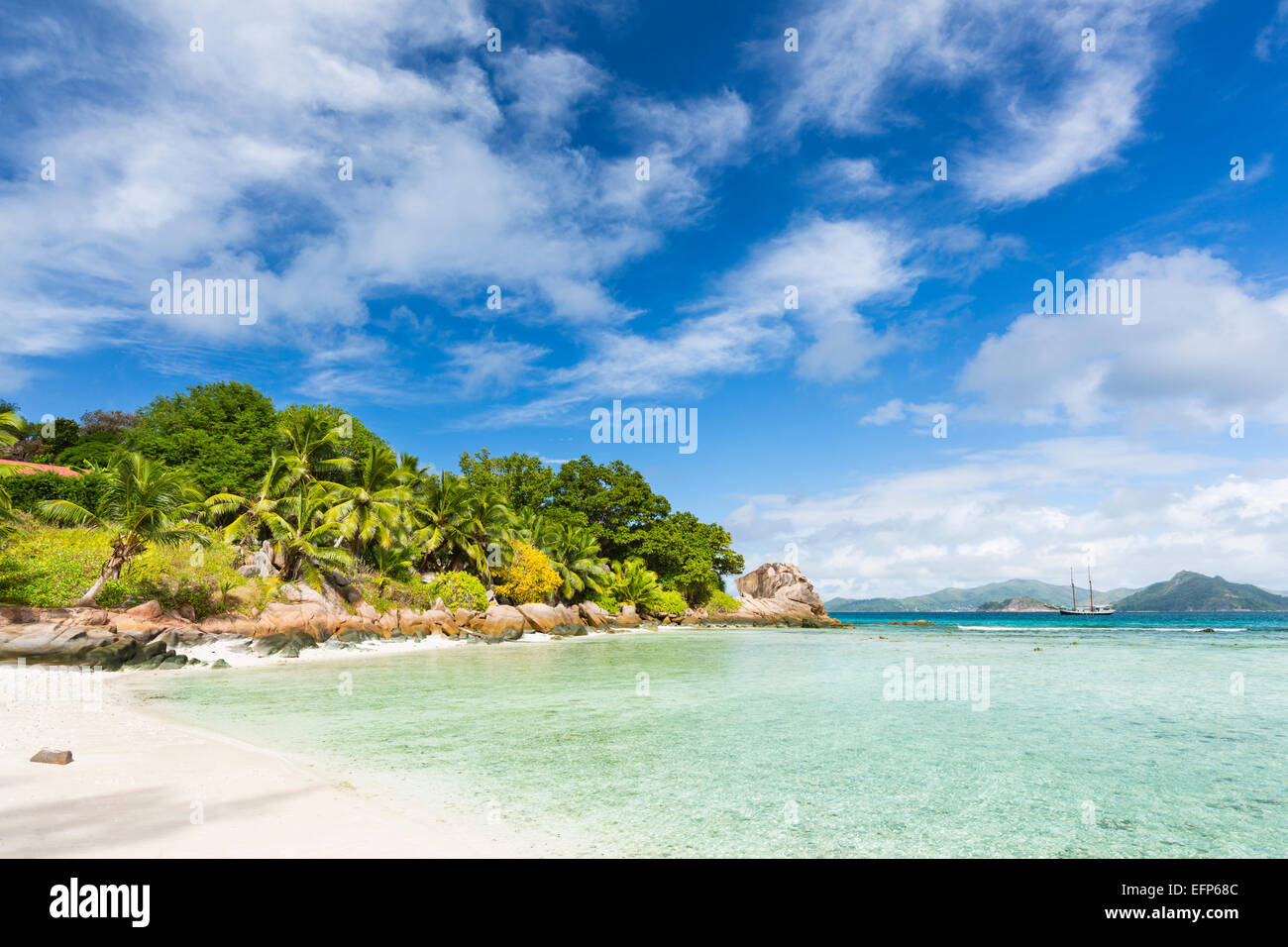 Calm water at Anse Severe in La Digue, Seychelles with palm trees and granite rocks in the background Stock Photo