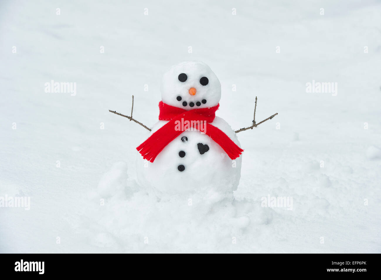 Happy snowman with a big coal heart and red scarf Stock Photo