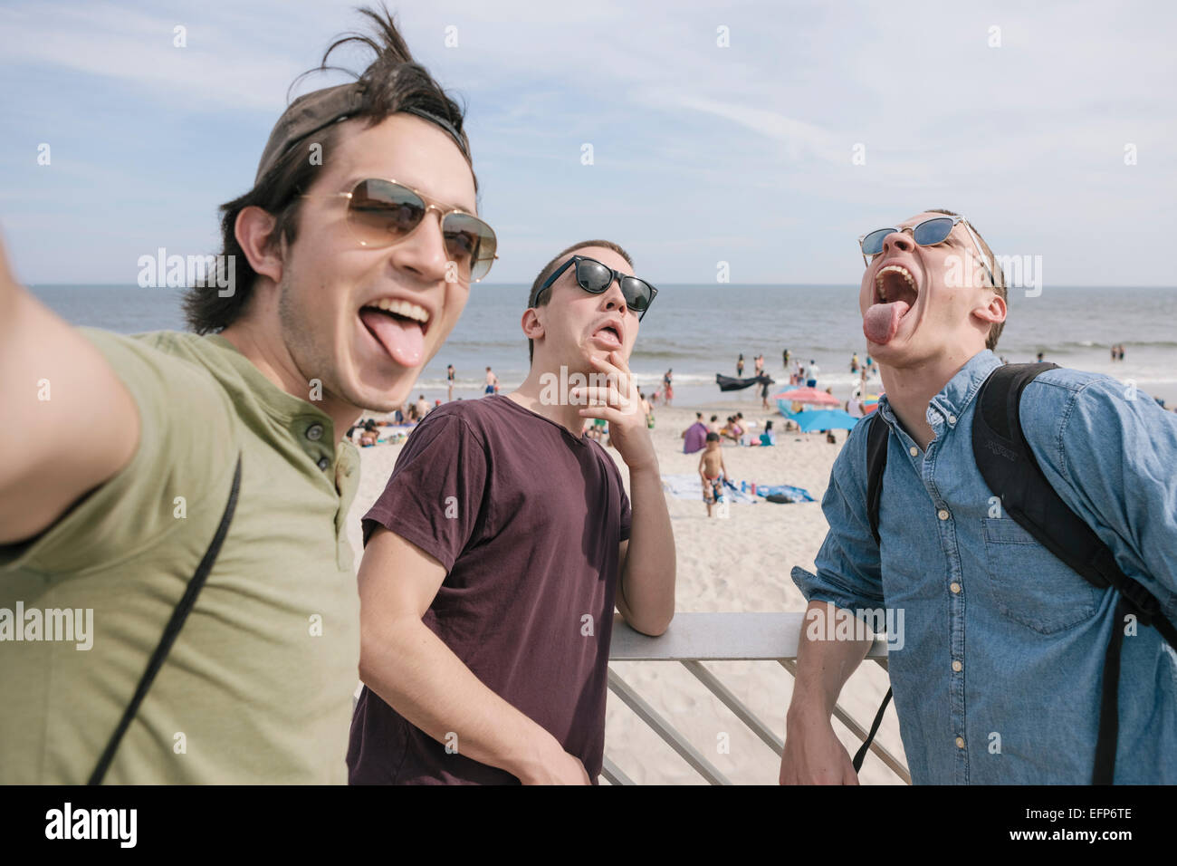 3 young male friends goofing while taking selfie at the beach Stock Photo