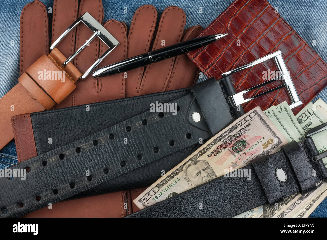 Pen, gloves, purses, belts and money on jeans background Stock Photo