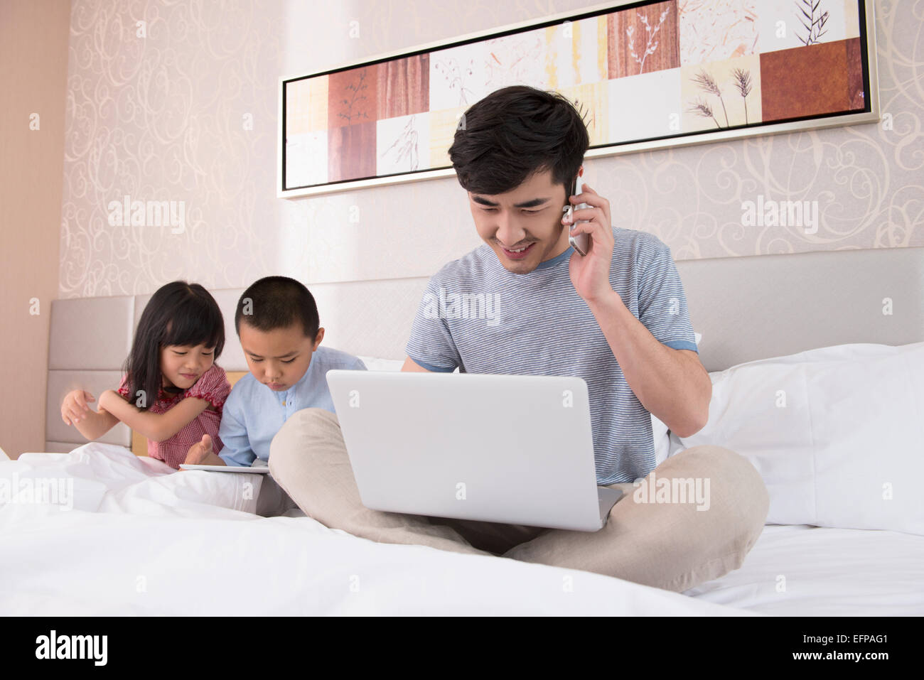 Father working on laptop in bed with children Stock Photo - Alamy