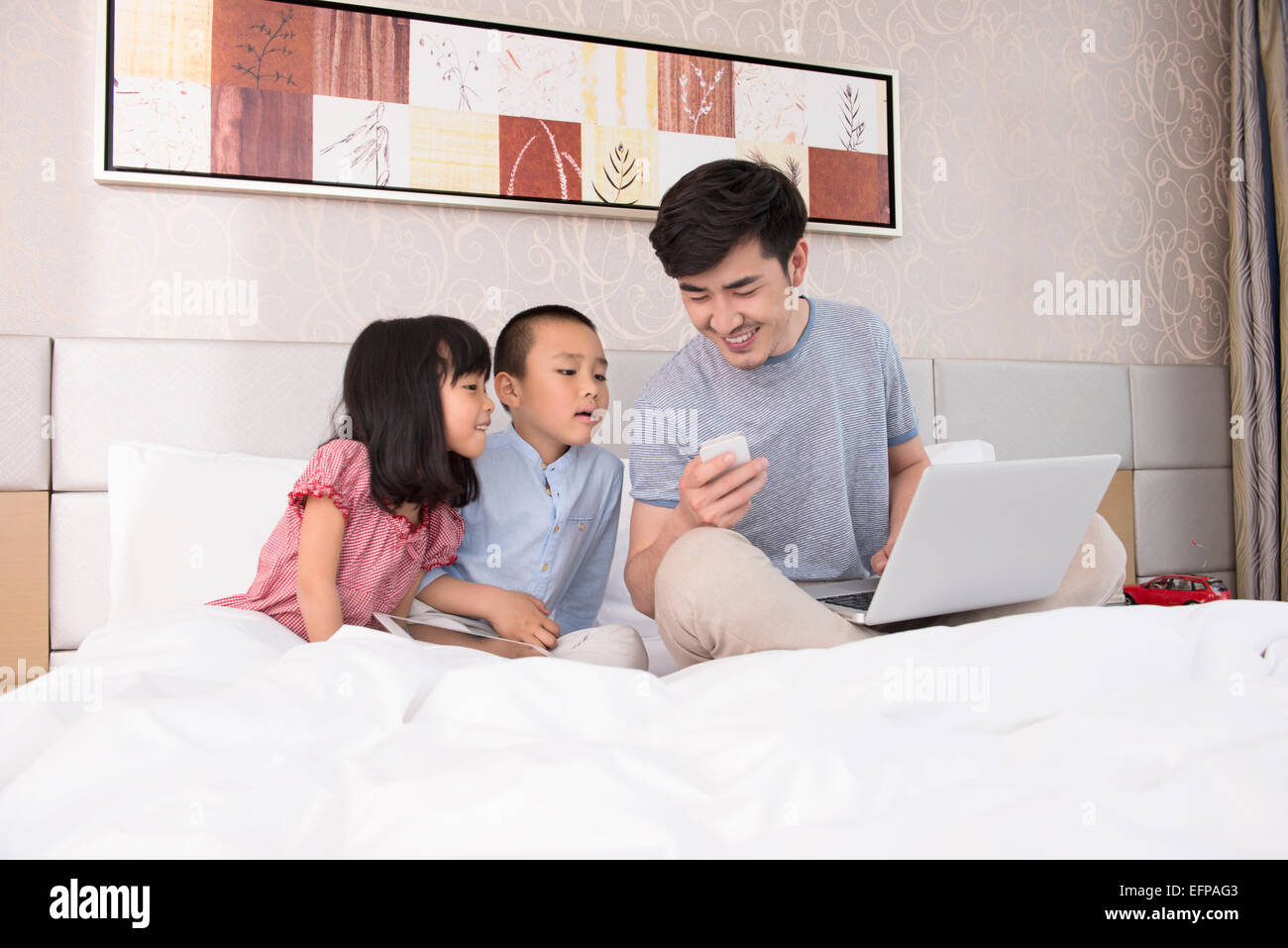 Father working on laptop in bed with children Stock Photo - Alamy