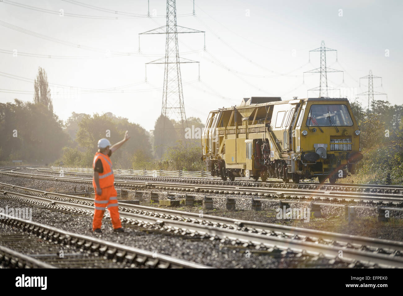 Rail worker signalling to maintenance train on railway Stock Photo
