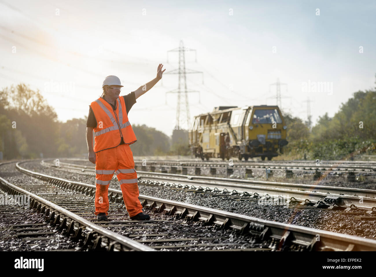 Rail worker signalling to maintenance train on railway Stock Photo