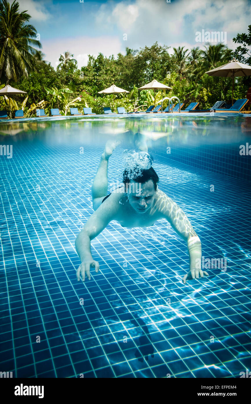 Man dives into a swimming pool views over the water and under water. Maldives. Stock Photo