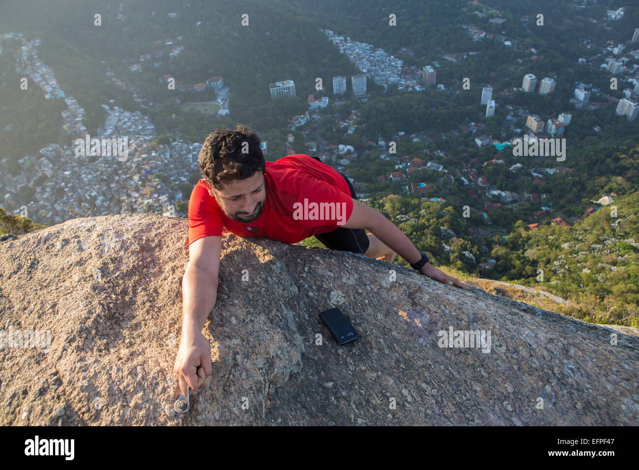 Climber on the top of the Morro dos Dois Irmaos (Two Brothers Hill) with Rocinha favela below, Rio de Janeiro, Brazil Stock Photo
