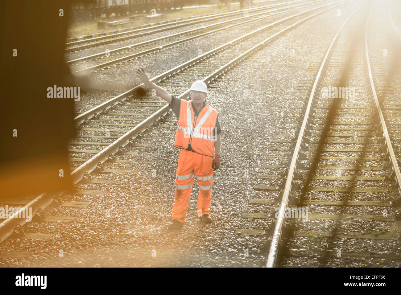 Railway worker signalling to train on railway Stock Photo