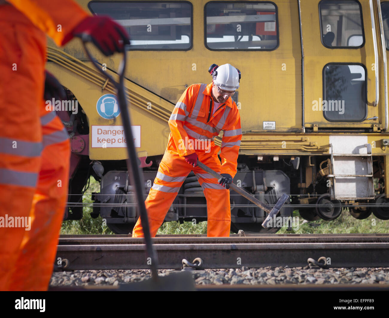 Railway maintenance worker tightening bolts on track Stock Photo
