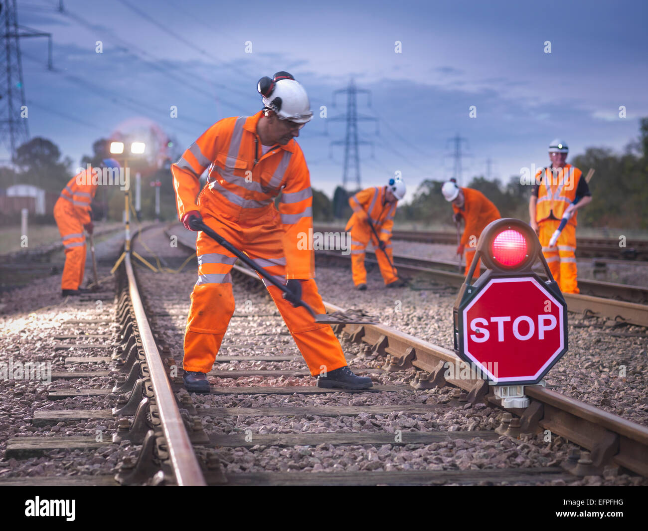 Railway maintenance workers on track with stop sign at night Stock Photo
