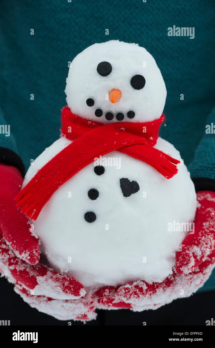 Red Gloved hands holding a snowman with a big heart Stock Photo