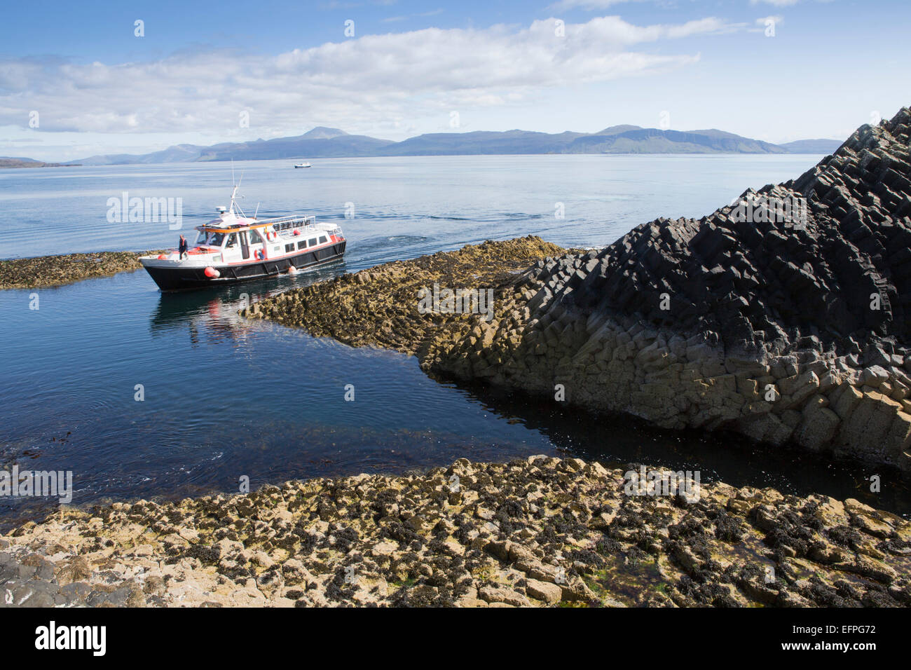 Basalt columns and a tourist ferry, Staffa Island, Inner Hebrides, Scotland, United Kingdom, Euorpe Stock Photo